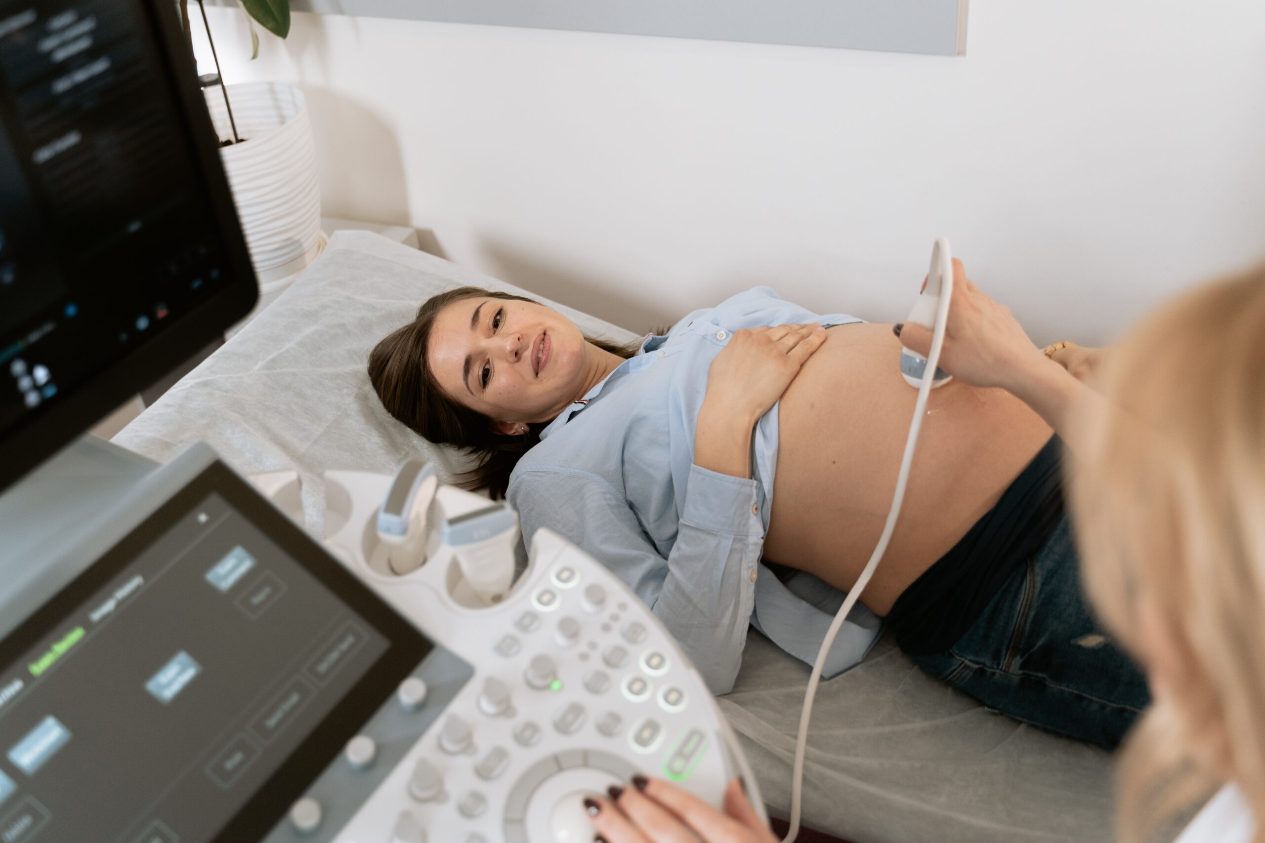 Kobieta w ciąży leżąca na kozetce podczas badania ultrasonograficznego