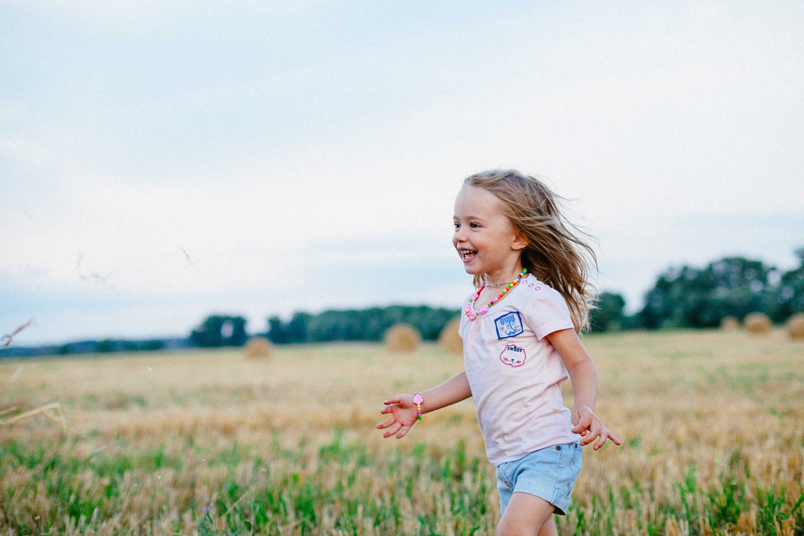 Mała śmiejąca się dziewczynka biegająca po zielonej łące